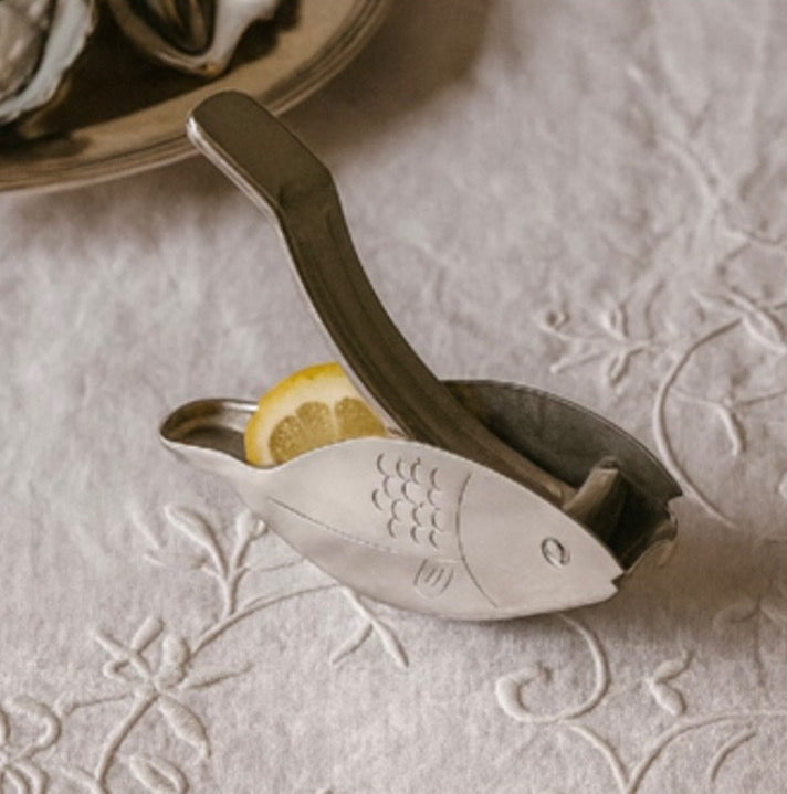 Metallic lemon squeezer with a lemon on a textured surface